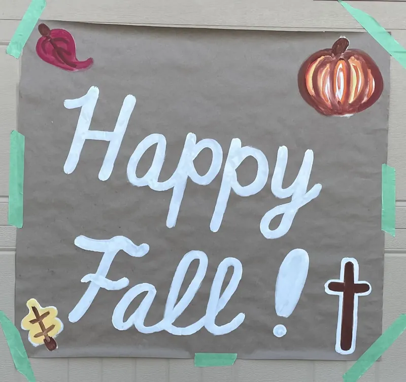 Hand-painted Happy Fall banner on grey paper with a pumpkin, acorn, autumn leaves and a cross