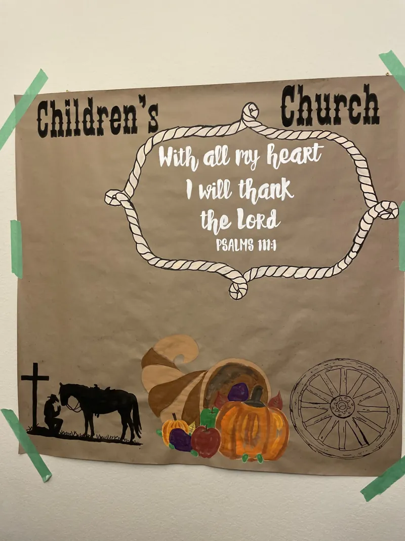 Tall hand-painted Thanksgiving children's church banner of Psalm 111:1 with a rope frame, a cowboy praying at a cross with his horse, a cornucopia and a wagon wheel
