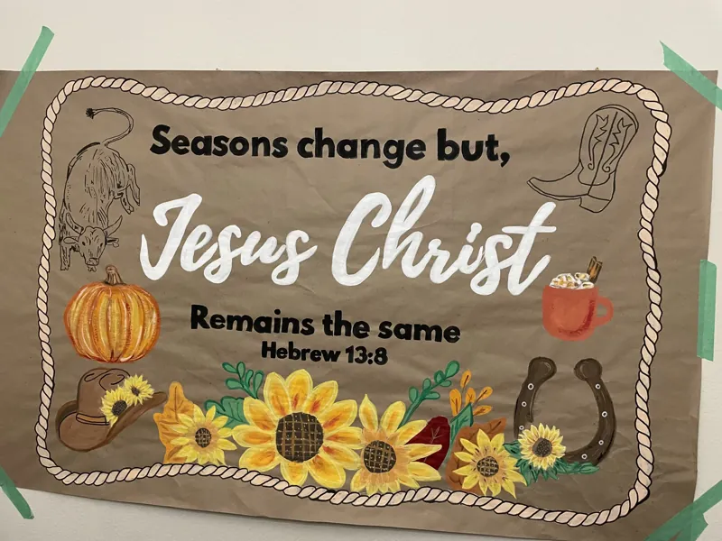 Hand-painted fall scripture banner of Hebrews 13:8 with a rope frame, sunflowers, a pumpkin, a cowboy hat, a boot, a horseshoe and hot cocoa
